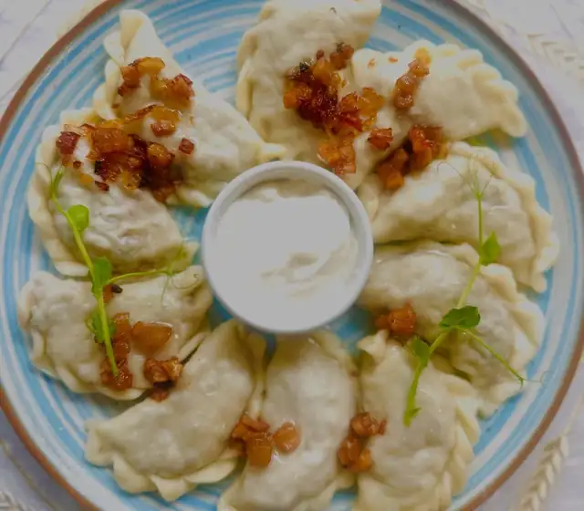 Pierogi z kaszą gryczaną i grzybami podawane ze skwarkami i śmietaną